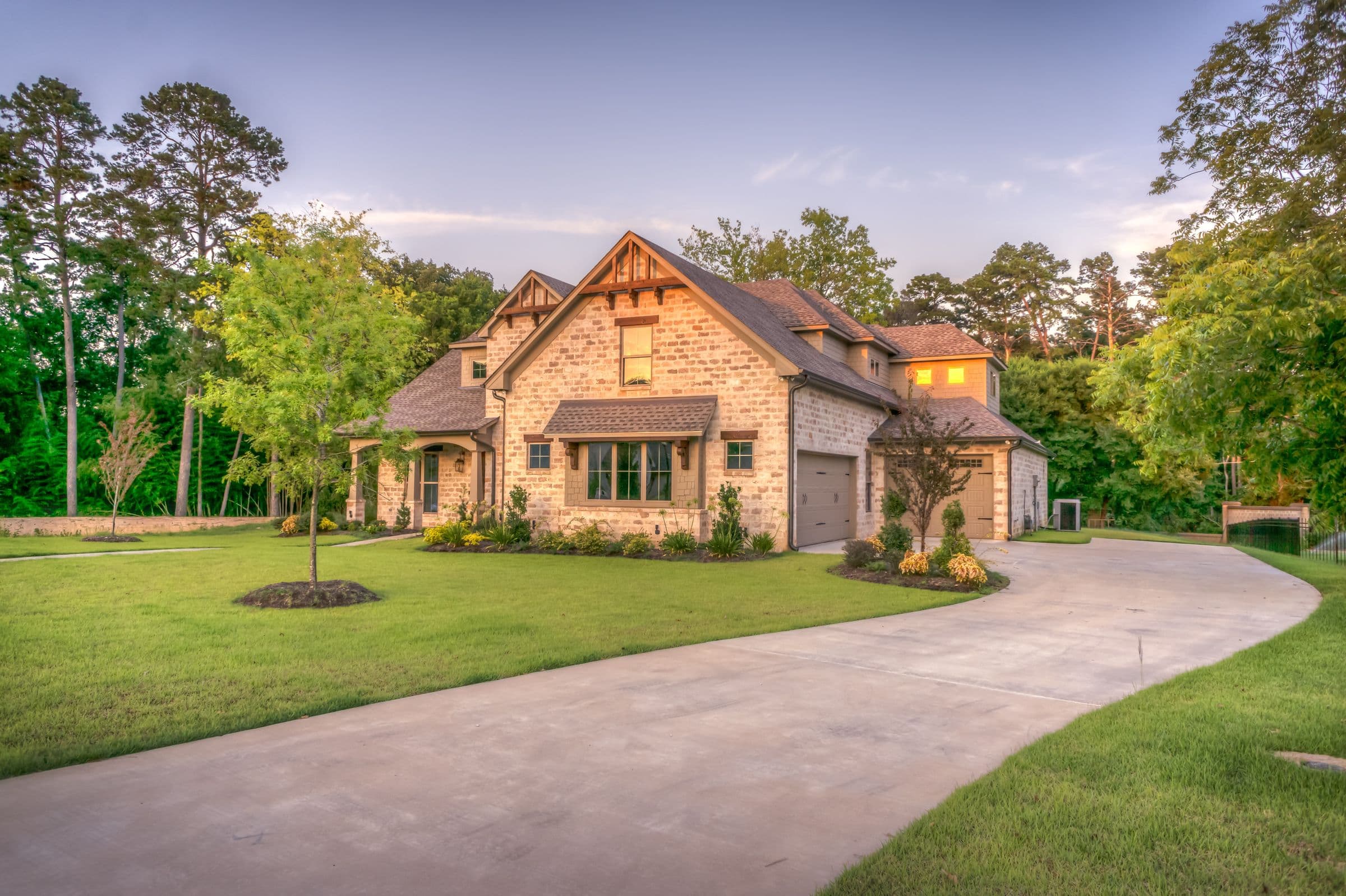 A two-story house with a manicured lawn in late-afternoon light, typical of improved suburban residential stock.